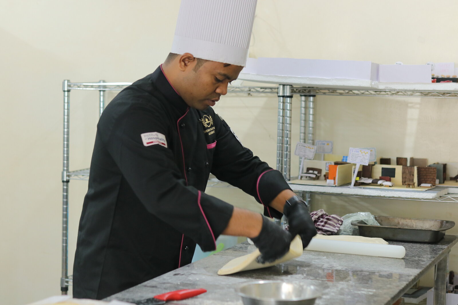 Indian Pastry Academy student laminating dough at the training kitchen bench