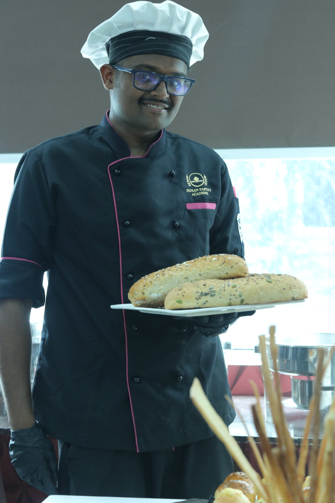 Indian Pastry Academy graduate presenting freshly baked seeded bread loaves